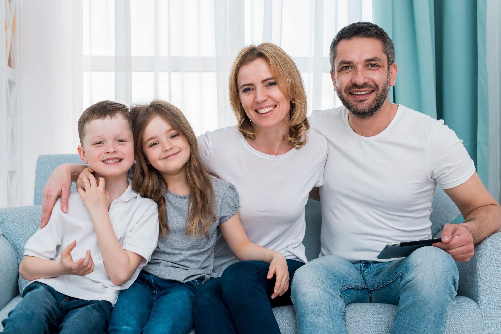 Smiling parents and two children representing dental care for the whole family.